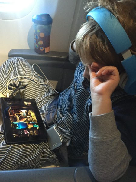 Child wearing headphone watching screen on airplane