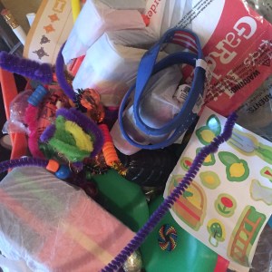 Random toys and free stuff in a pile including stickers, pipe cleaners, sunglasses, and mini frisbees