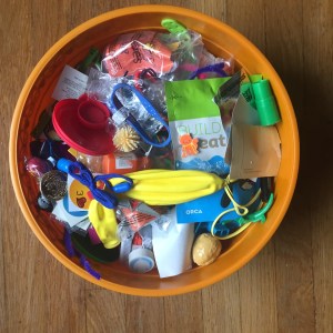 Large orange bowl filled with small plastic toys, stickers, sunglasses, balloons, and more for trick or treating