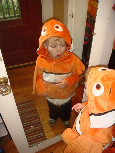Child looking in mirror while wearing Disney Nemo clownfish costume hooded