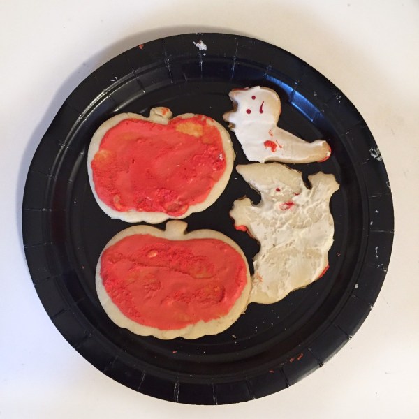 Halloween sugar cookies pumpkins with orange frosting, white ghost, half eaten cat