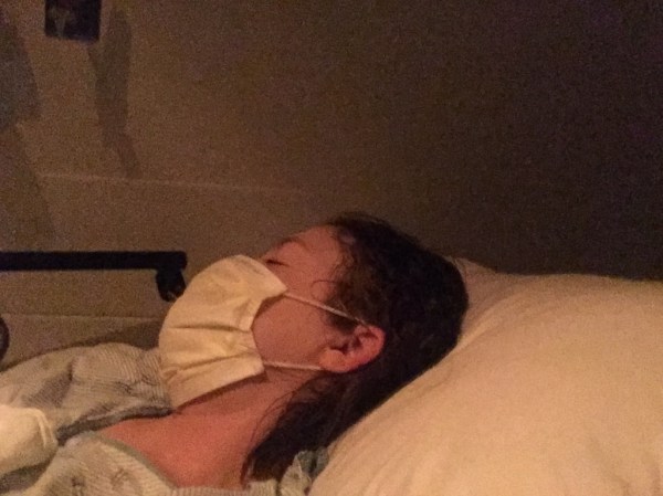 Woman in hospital bed with mask covering lower face