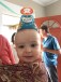 Toddler riding in ring sling wearing an Octonauts party hat