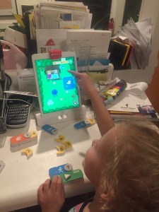 Child manipulating screen in Osmo's Coding with Awbie game