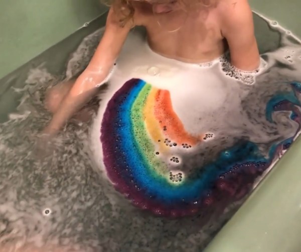 Bella Grace Bath Company Rainbow Bath Fizzy in tub water with child