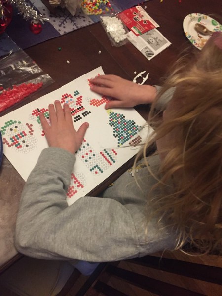 Child creating working making melty bead Perla christmas ornaments decorations with patterns