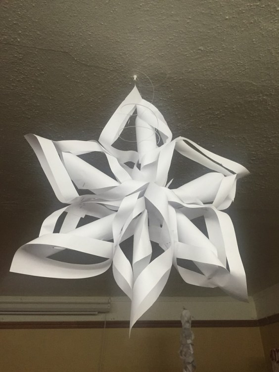 Giant paper snowflake kid made hanging from ceiling decoration winter