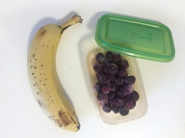 Ripe banana and frozen blueberries in container leftover fruit kid snack smoothie mix