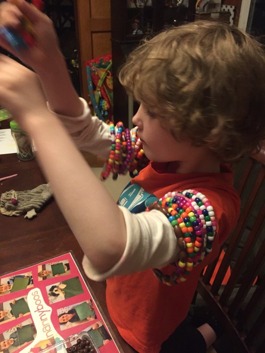 Child making bracelets from plastic pony beads and pipe cleaners