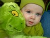 Infant in green hat and green shirt with green Grinch stuffed animal toy