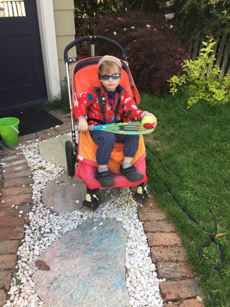 Preschooler in sunglasses riding in Bugaboo Frog stroller on gravel path