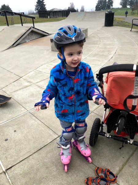 Child wearing roller blades inline skates adjustable and helmet and wrist guards and knee pads outside on concrete skating area