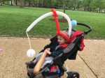 Two and a half year old child riding in BOB motiong stroller with balloon baseball bat and baseball to swing at