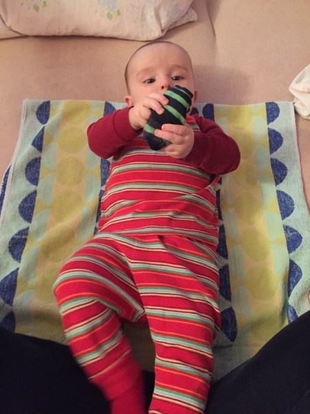 Infant laying on bed on towel for diaper changing