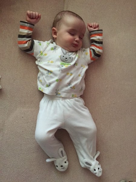Baby infant dressed in first easter shirt and pants with bunny feet