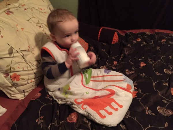 Infant drinking from bottle while wearing a sleep sack