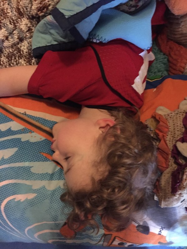 Four year old napping on closet floor with pillows and blankets