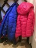 Pink and blue children's puffy winter coats hanging side by side