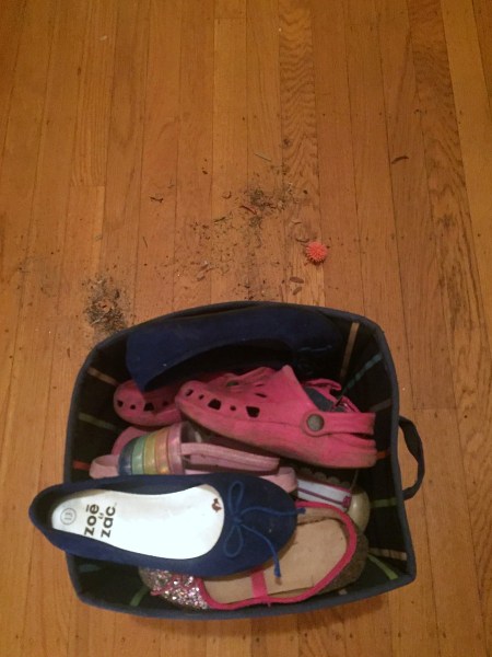 Bin full of shoes next to piles of sand and dirt on the floor