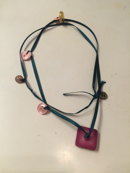 Button necklace made by child strung on ribbon