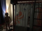 Child silhouette next to bed curtains hanging from upper bunk bed to partition lower bunk