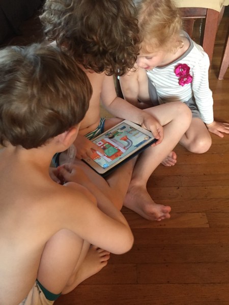Three kids sharing one iPad playing Toca Life Farm app cooperatively