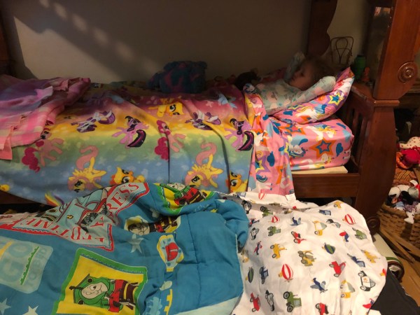 Bunk bed with trundle and pink kid unicorn sheets and white construction vehicle sheets