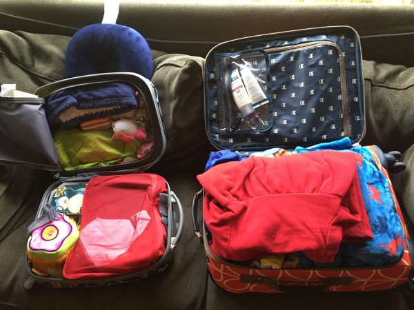 Child's suitcase and roller board packed for three day travel with three kids