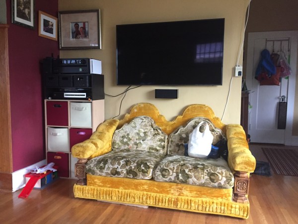 TV with love seat underneath yellow velour with green leaf pattern cushions