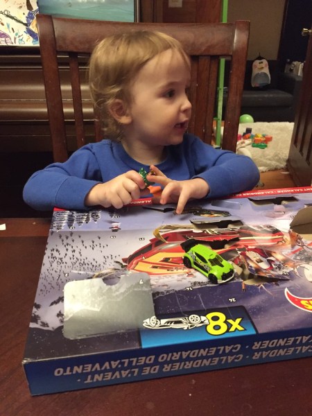 Child with Hot Wheels Advent calendar box with one door open and car sitting on top
