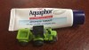 Driven pocket series tiny truck green tractor with trailer next to Aquaphor on the go tiny tube of healing ointment