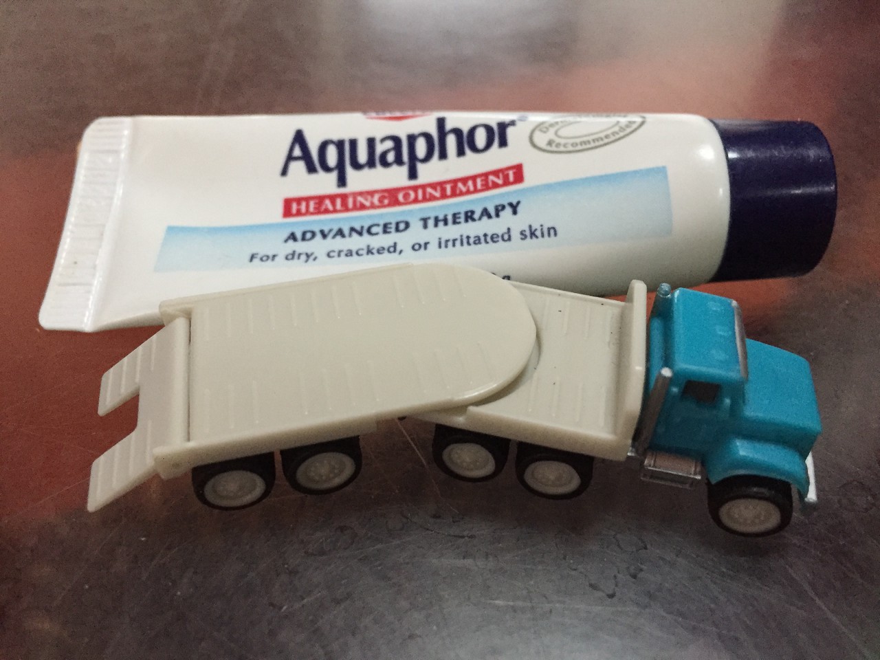 Aquaphor tiny tube healing ointment by Eucerin next to Driven pocket series flatbed truck vehicle toy