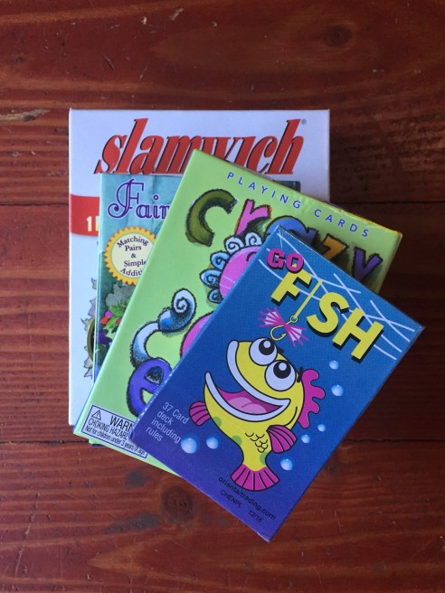 Card games for kids Go Fish Crazy Eights Fairy Queen and Slamwich stacked on floor in boxes