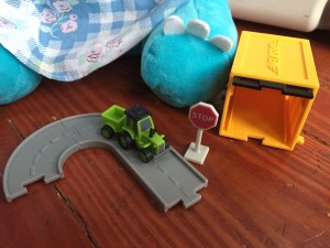 Driven Pocket Series vehicles with opening garage in yellow and black, green tractor with trailer, three connecting gray road pieces, and tiny stop sign