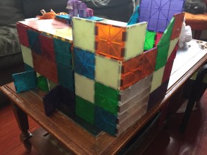 Magna-Tiles creation structure built on coffee table with Lego animals on top