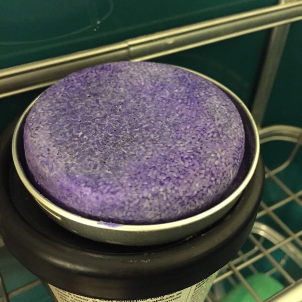 LUSH solid shampoo in reusable tin inside shower caddy