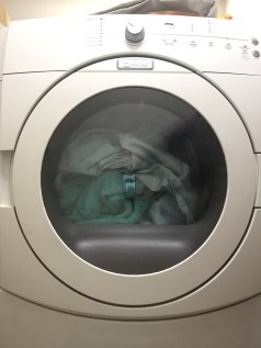 Front load gas Maytag dryer filled with laundry sheets towels