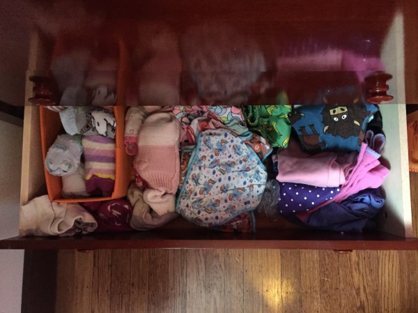 Laundry clothes put away in bottom drawer of child's dresser socks in bin underwear pajamas swim suits