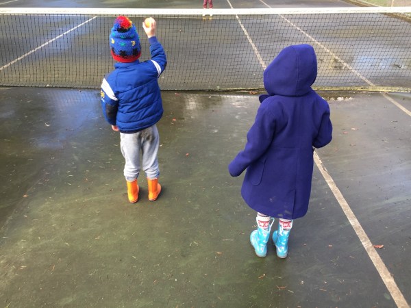 Two kids wearing Norty rain boots in orange and blue unicorn and rainbow print