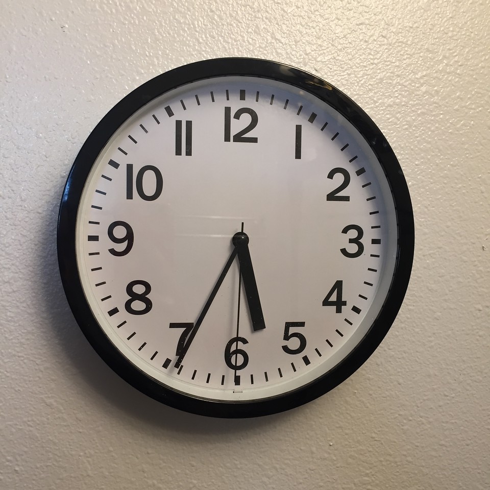 Round clock with numbers analog at 5:34 on white wall
