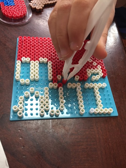Child using tweezers to make Perle bead creation