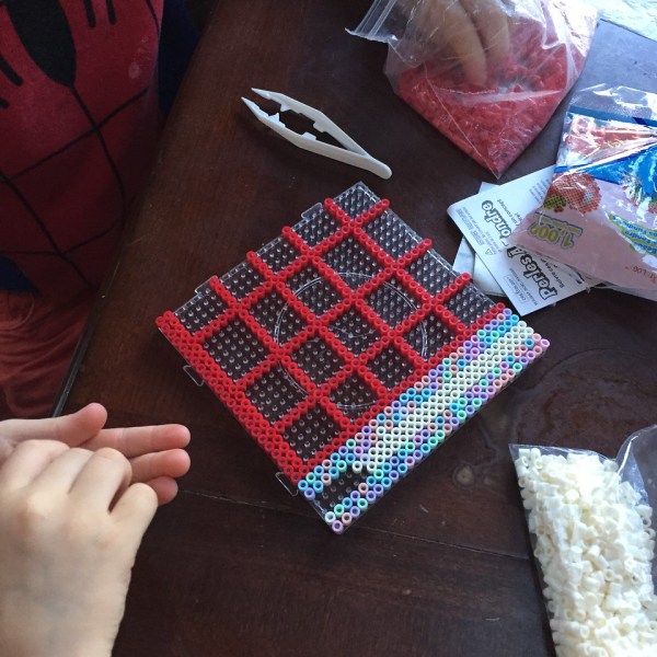 Perle beads on clear pegboard with kids' hands holding beads