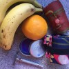 Bananas, oranges, LUSH purple solid shampoo, reusable razor, envirosax reusable bags on counter