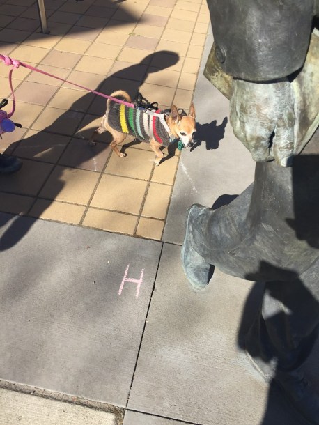 Letter H drawn in sidewalk chalk next to statue