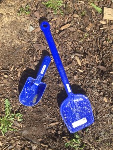 Spielstabil small sand scoop and short handled classic spade shovel in bright blue laying in dirt