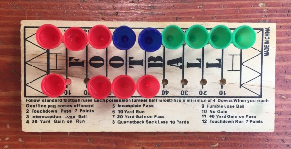 Football peg game board with blue red and green pegs and dice roll rules written on bottom