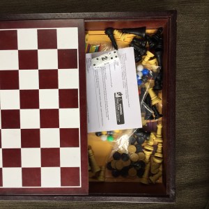 Five game in one box checkerboard lid slid open to reveal instructions and pieces for backgammon, chess, checkers, Chinese checkers, and pickup sticks
