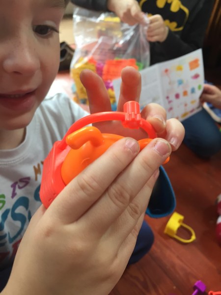 Child holding up orange dog in ferris wheel seat Gears! Gears! Gears! pet play land building set from Learning Resources
