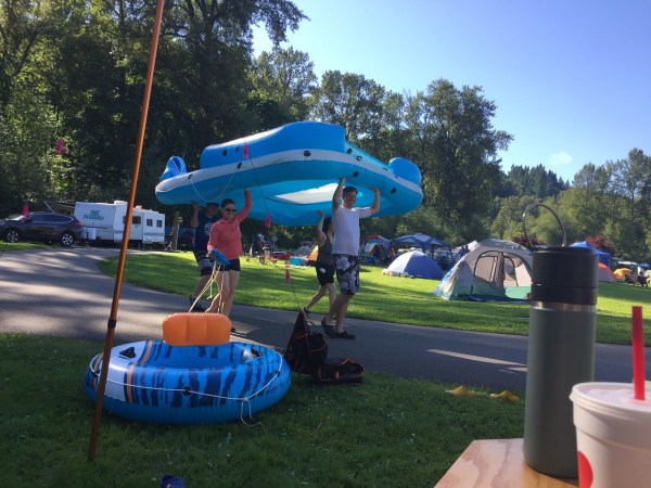 Adults carrying H20Go Bahama Wave Island Float at campsite