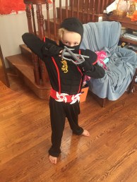 Eight year old girl dressed up in ninja costume with black face mask